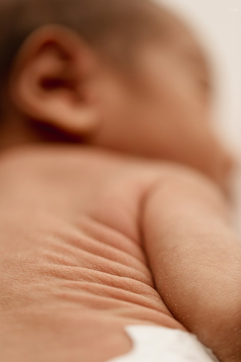 Close-up of the soft folds on a newborn's back, natural window light