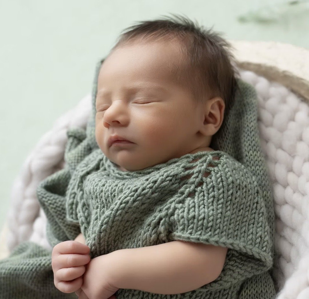 Sleeping newborn in a green knit romper, in-hospital newborn photography