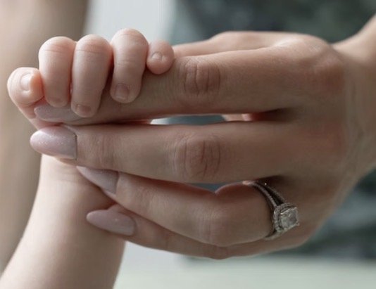 Newborn's hand wrapped around a mother's finger