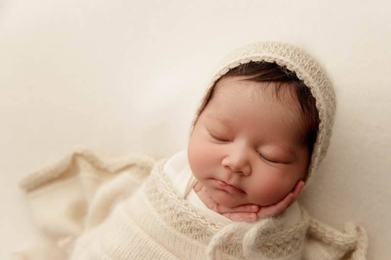 Newborn in a knit bonnet asleep during an in-hospital newborn photography session