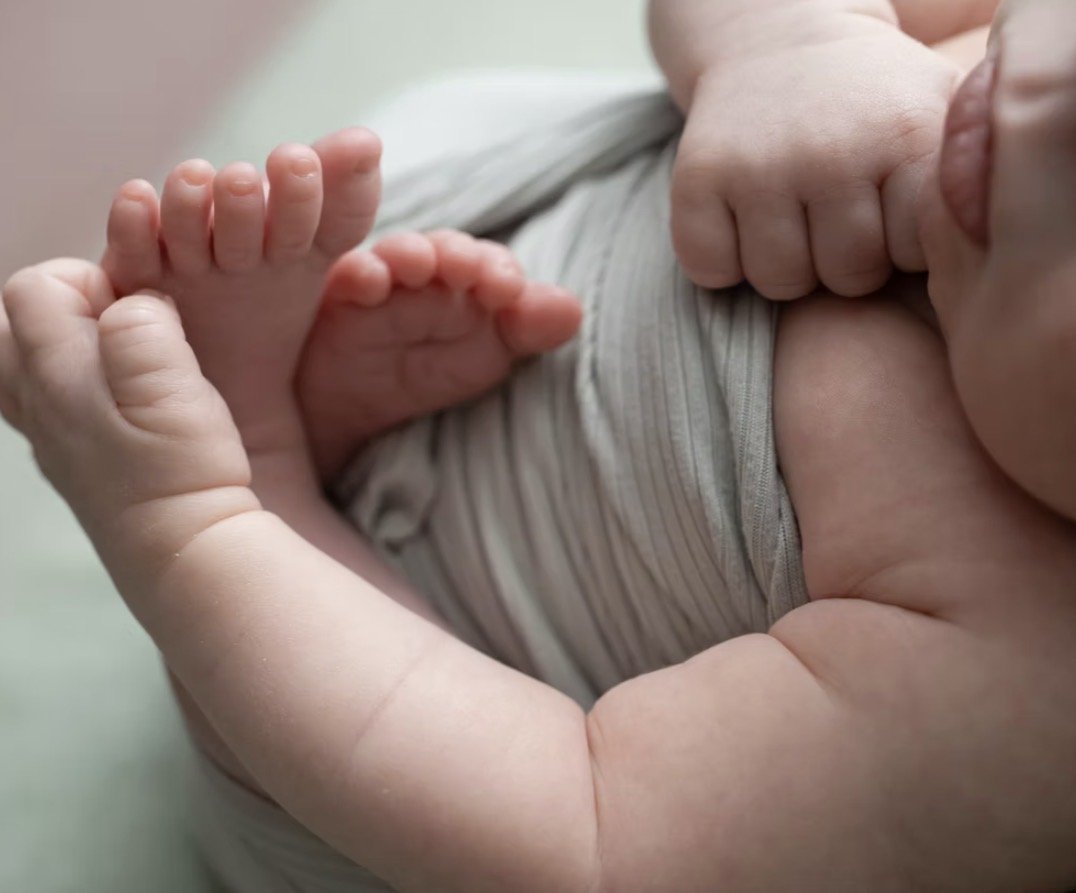 Newborn toes and hands in a sage wrap