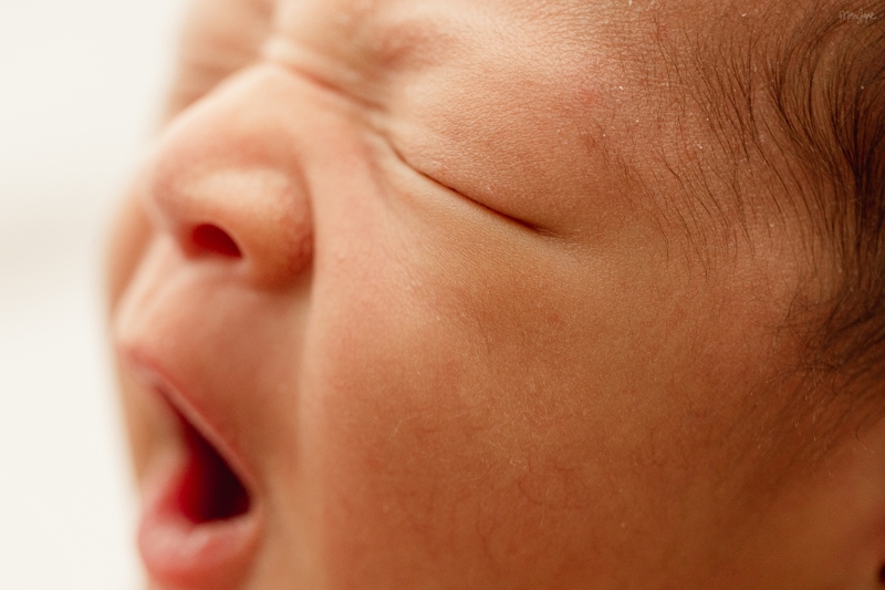 Close-up of a newborn mid-yawn, photographed in soft hospital window light