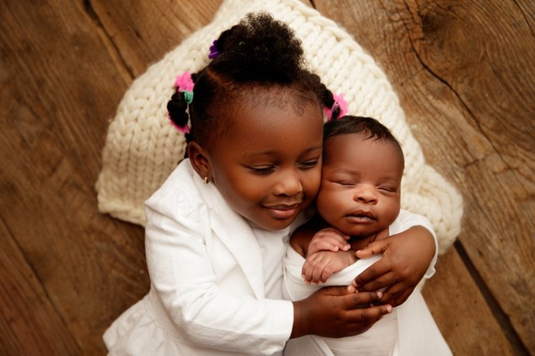 Toddler sister cuddling her newborn baby sister in the hospital